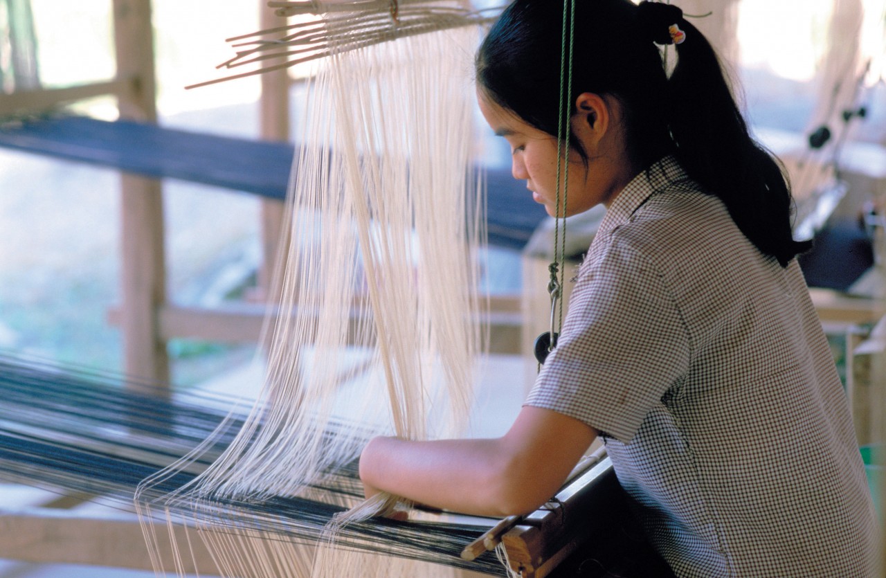 Jeune femme à l'oeuvre sur son métier à tisser.